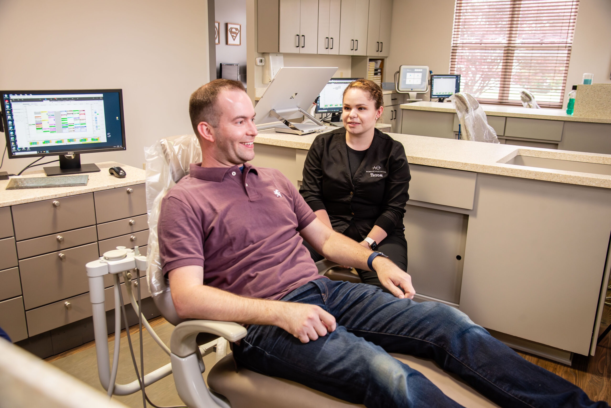 Male patient smiling with office staff in patient chair