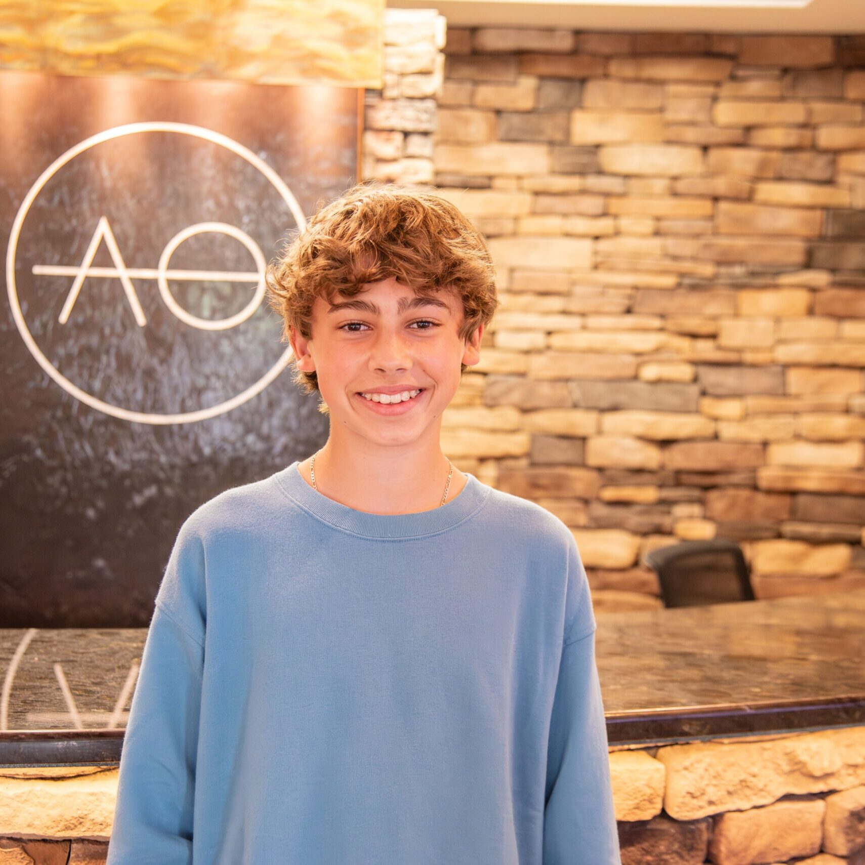 Male teen patient smiling in front of logo